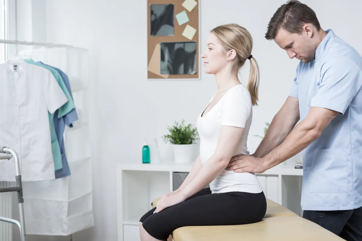 Young physiotherapist doing lumbar spine mobilization